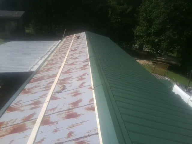 Old rusted panels beside newly installed green metal roofing — Wind Damage Roof Repair by Roofing Brothers in Union Grove
