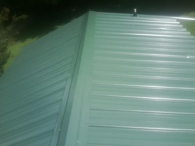 New green metal panels meeting at the ridge of a roof in Union Grove