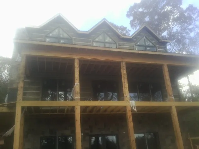 Dormers and porch framing on a large log home under construction — Roof Coating work by our crew in Union Grove